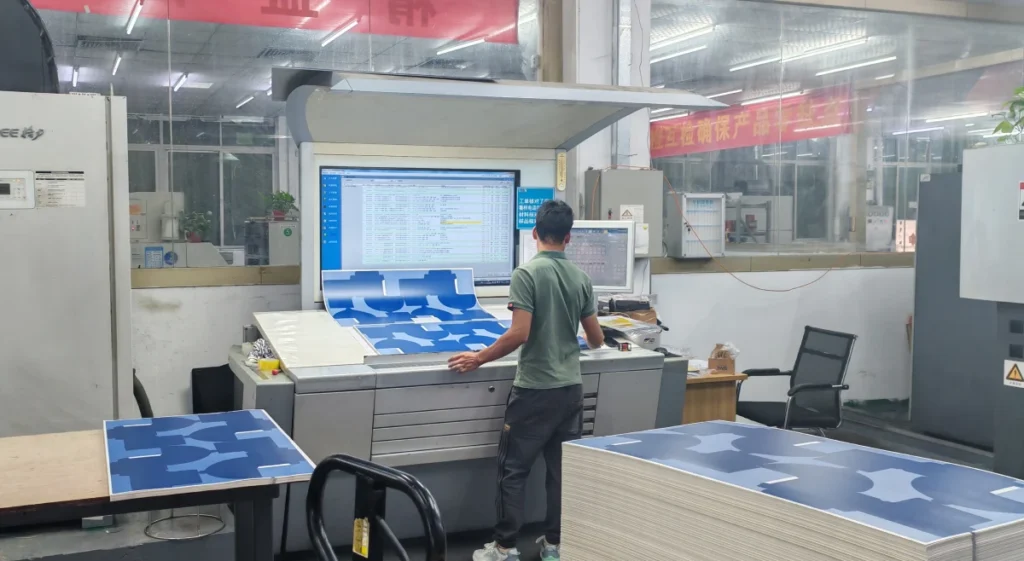 A worker inspecting print quality on a control panel in a packaging production facility.