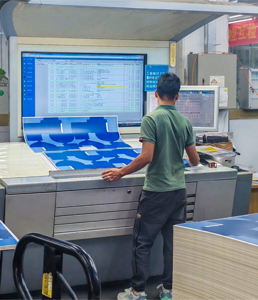 A printing technician inspecting color samples and print details on a high-precision printing machine.